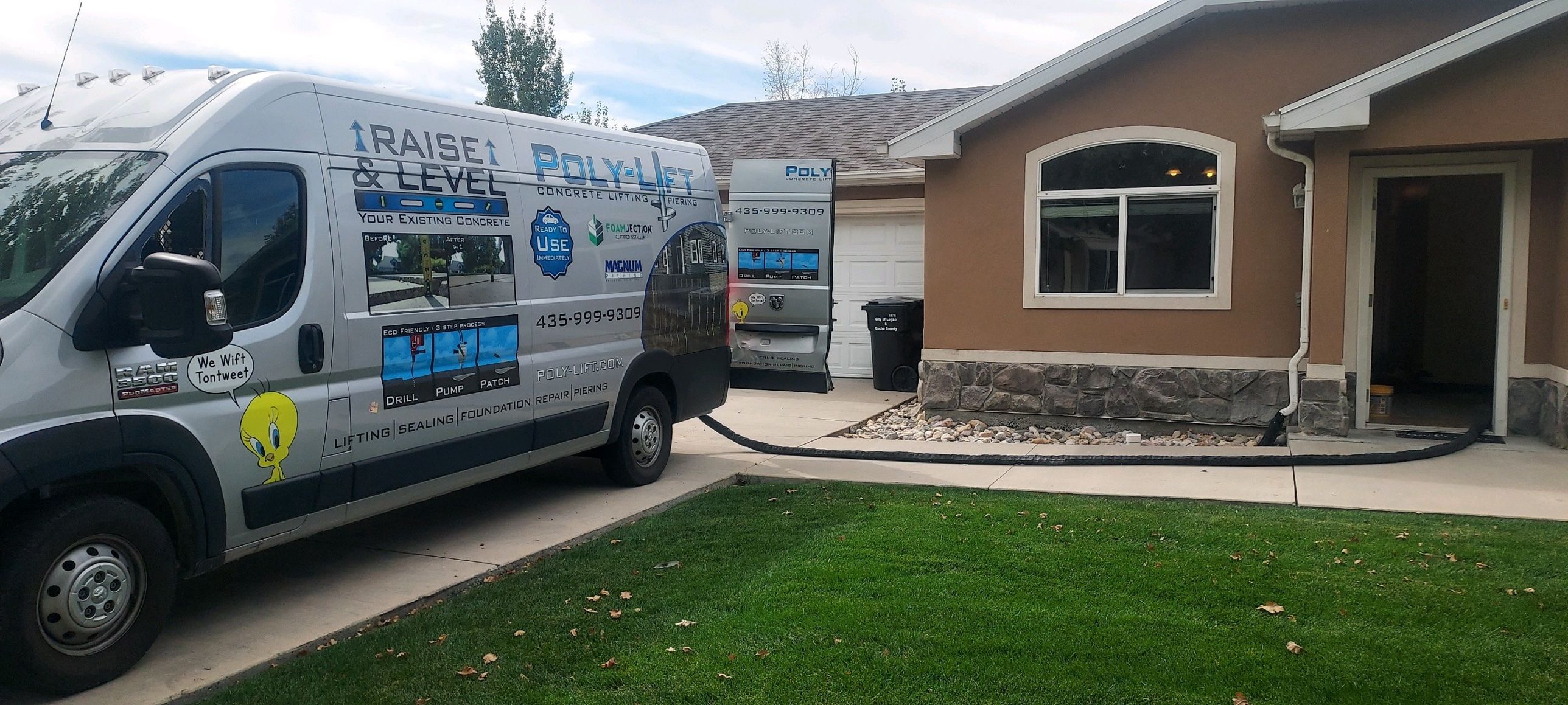The wrapped Poly-Lift van and foam rig parked at a Logan, Utah home with hoses running inside for a concrete lifting job